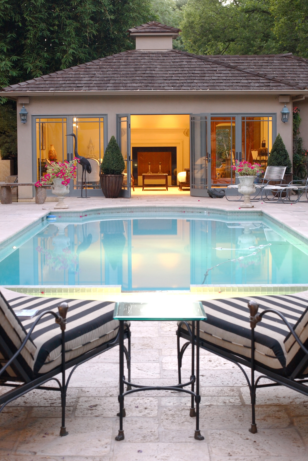 Backyard Pool House Two lounge chairs over look an inviting pool and a pool house