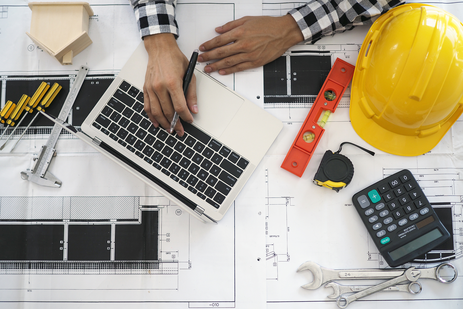 Engineers Work With Laptops And Blueprints. Calculate And Check Engineers work with laptops and blueprints. Calculate and check the construction project.