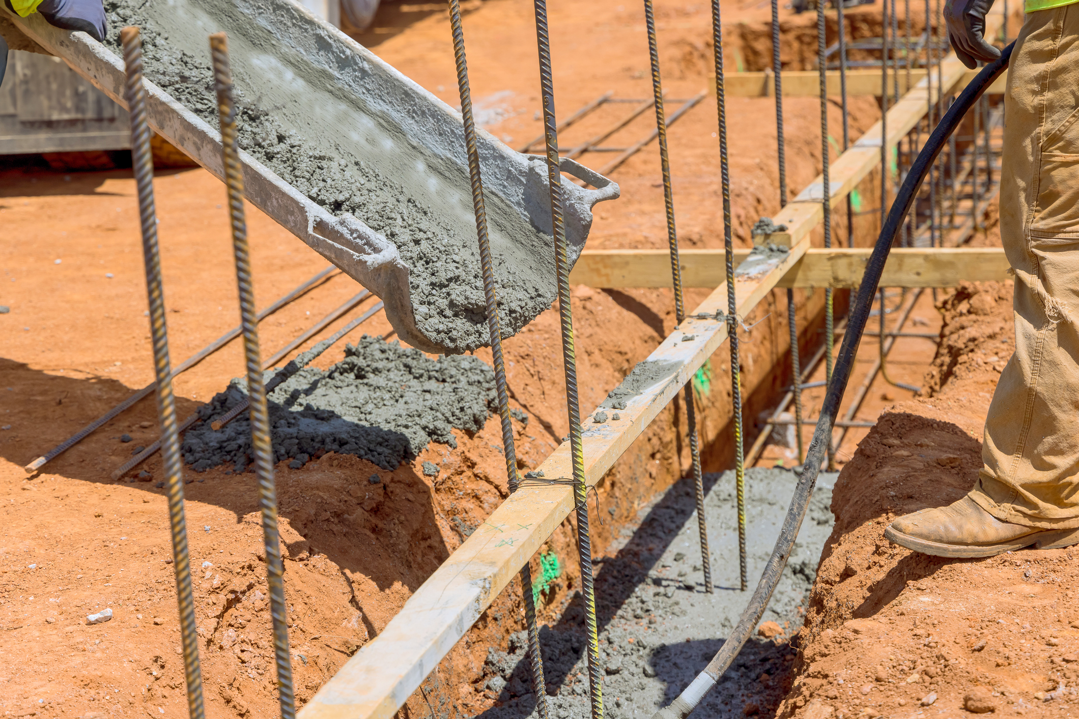An individual laying cement concrete to trenches in preparation for foundation of a house An individual laying cement concrete to trenches in preparation for foundation of house
